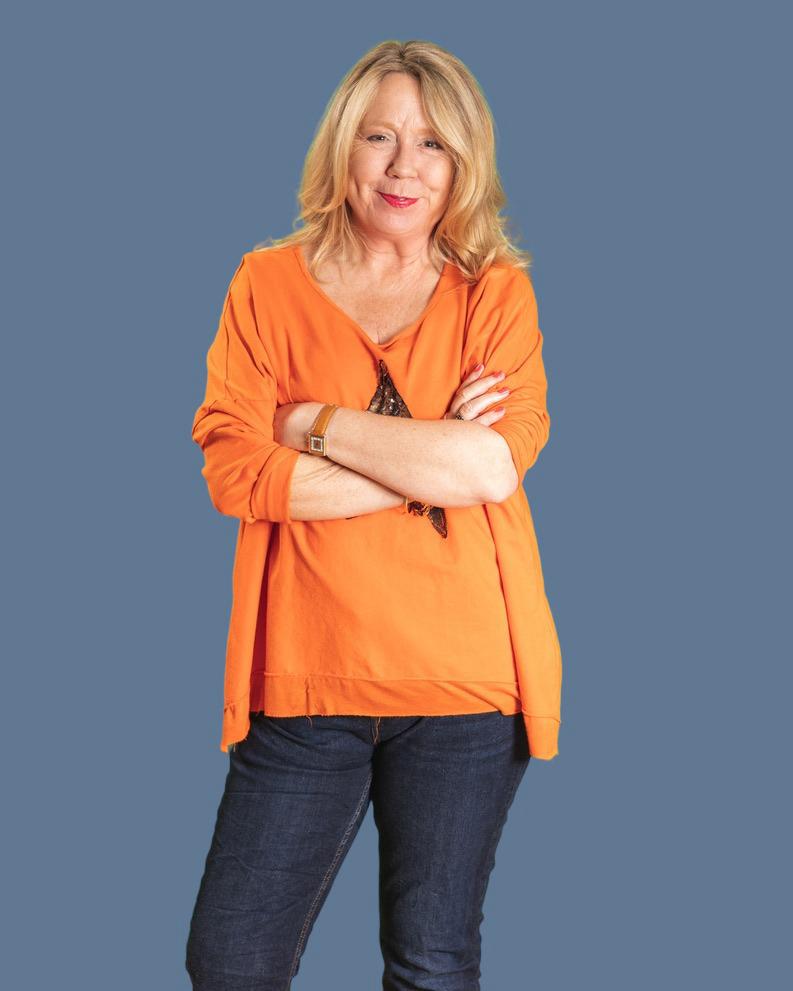 Smiling woman in orange top against grey background.